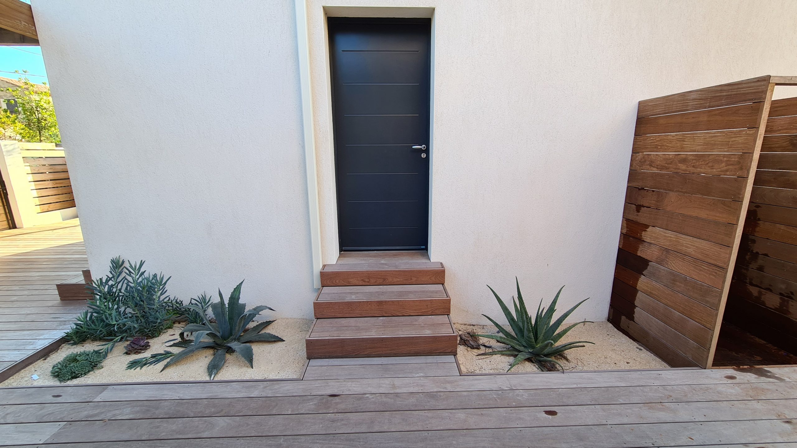 Photo d'une porte avec un petit escalier en bois et une terrasse en bois